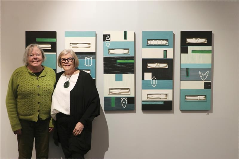 Artists Rachel Hirabayashi and Megan Huffadine stand with some of the paintings at new exhibit at He Waka Tuia, called Indigo.