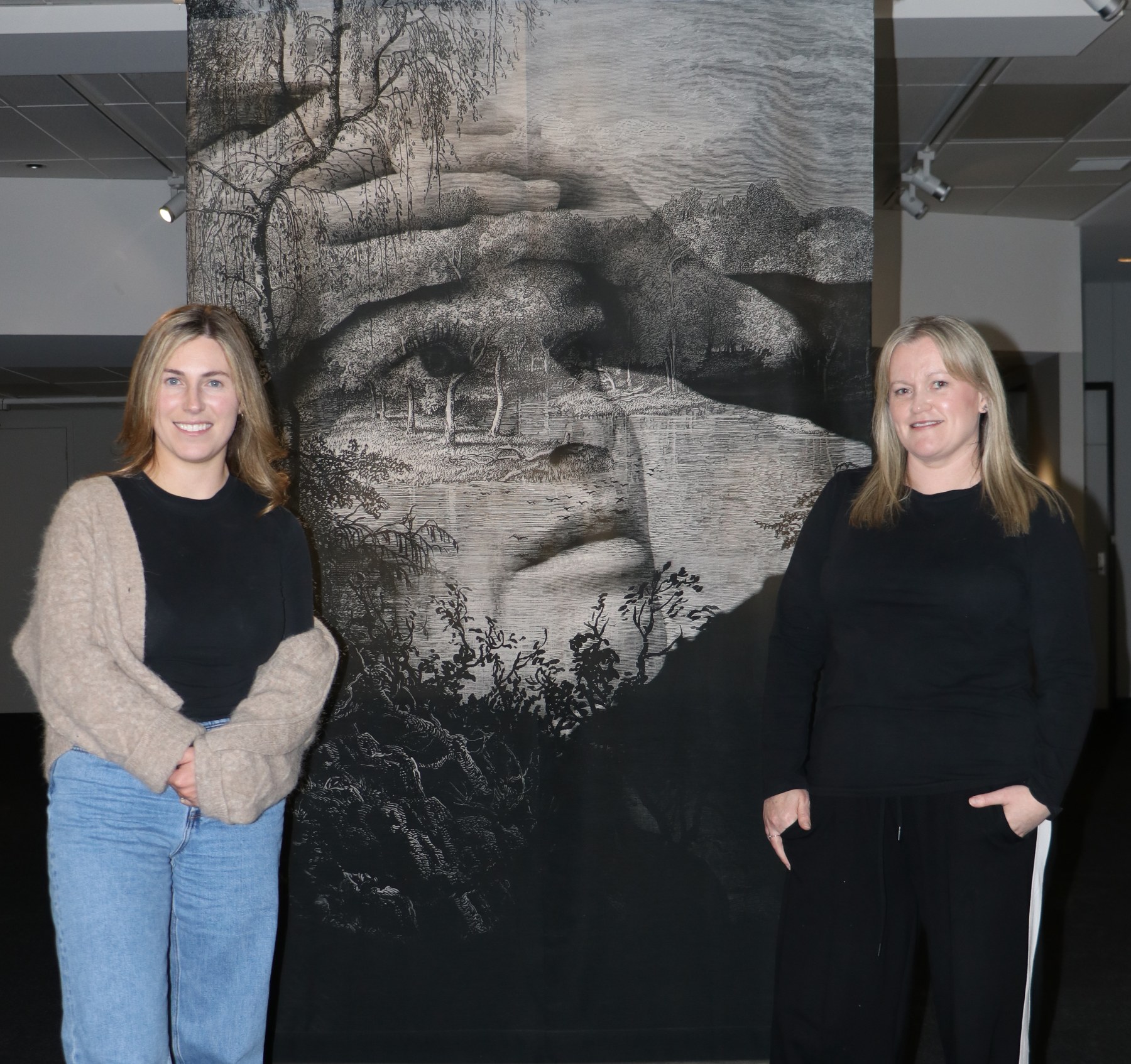 He Waka Tuia Senior Curator: Exhibitions Gemma McDonald (left) and He Waka Tuia Manager Sarah Brown, with a silk print by artist Prue MacDougall ahead of the opening of Small Holes in the Silence at He Waka Tuia, in Invercargill.