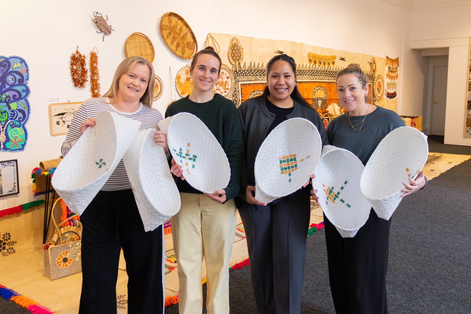 Staff from He Waka Tuia and Mīharo Murihiku stand with some of the Pasifika artworks that will be displayed at this year's Polyfest event.