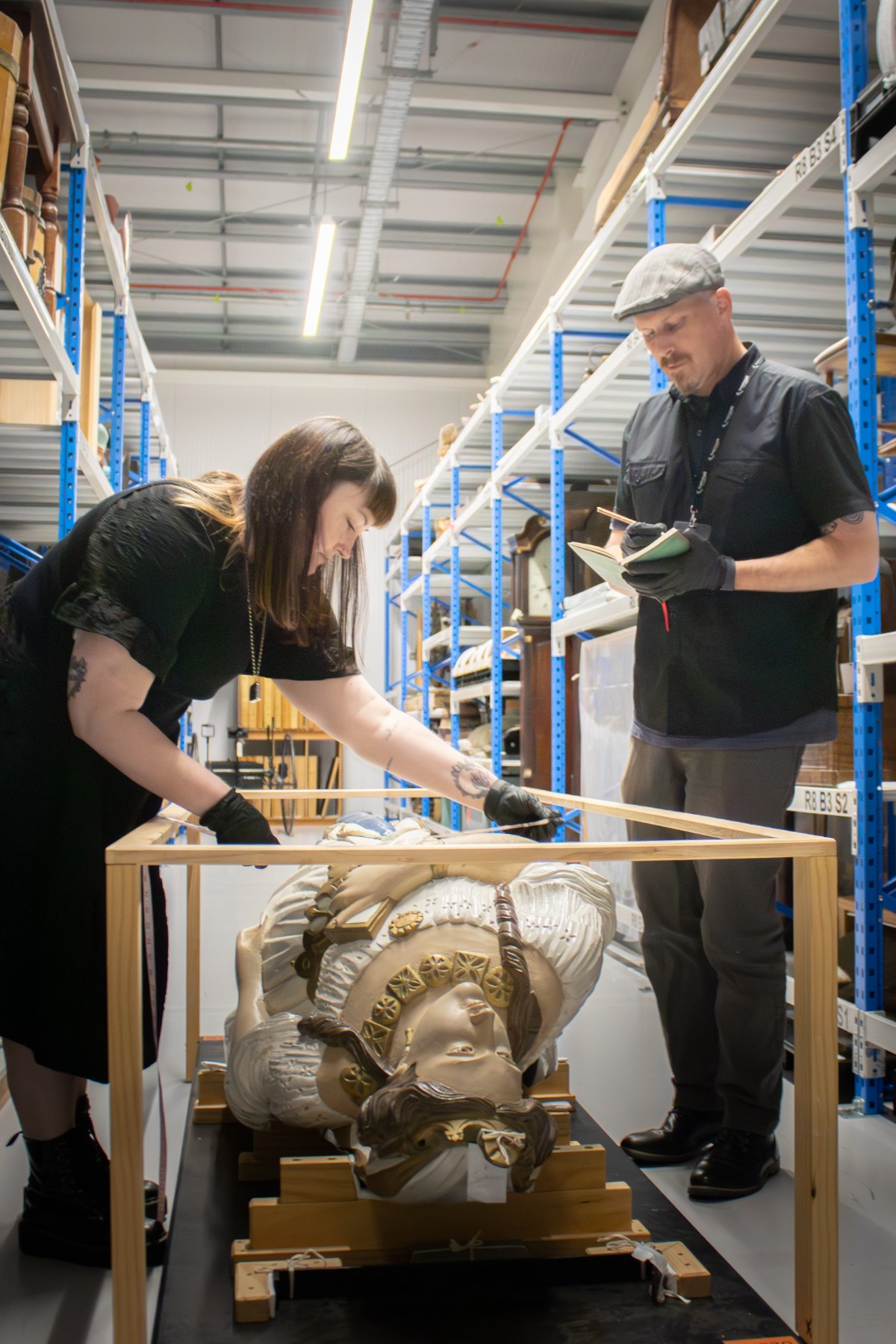 Te Unua Museum of Southland Senior Curator Sarah Robinson and Team Leader Experience David Dudfield inspect the figurehead from the barque, England's Glory, in the Te Pātaka Taoka regional collections storage facility.