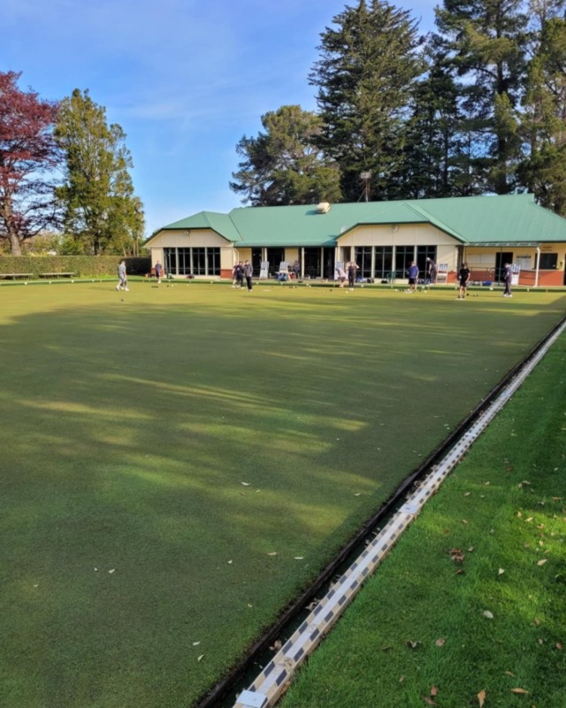 A pavilion building with an outdoor lawn bowls green in front. 